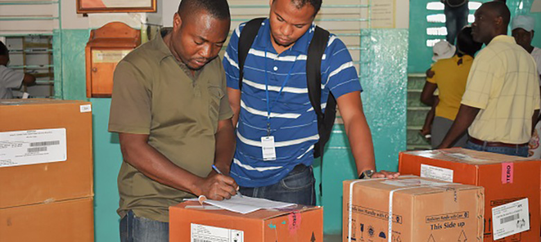 Workers in Haitian health facility verify delivery of ARVs surrounded by boxes of commodities