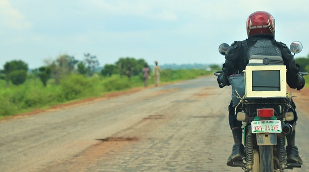 Image of a person on a motorcycle carrying lab samples in Nigeria.