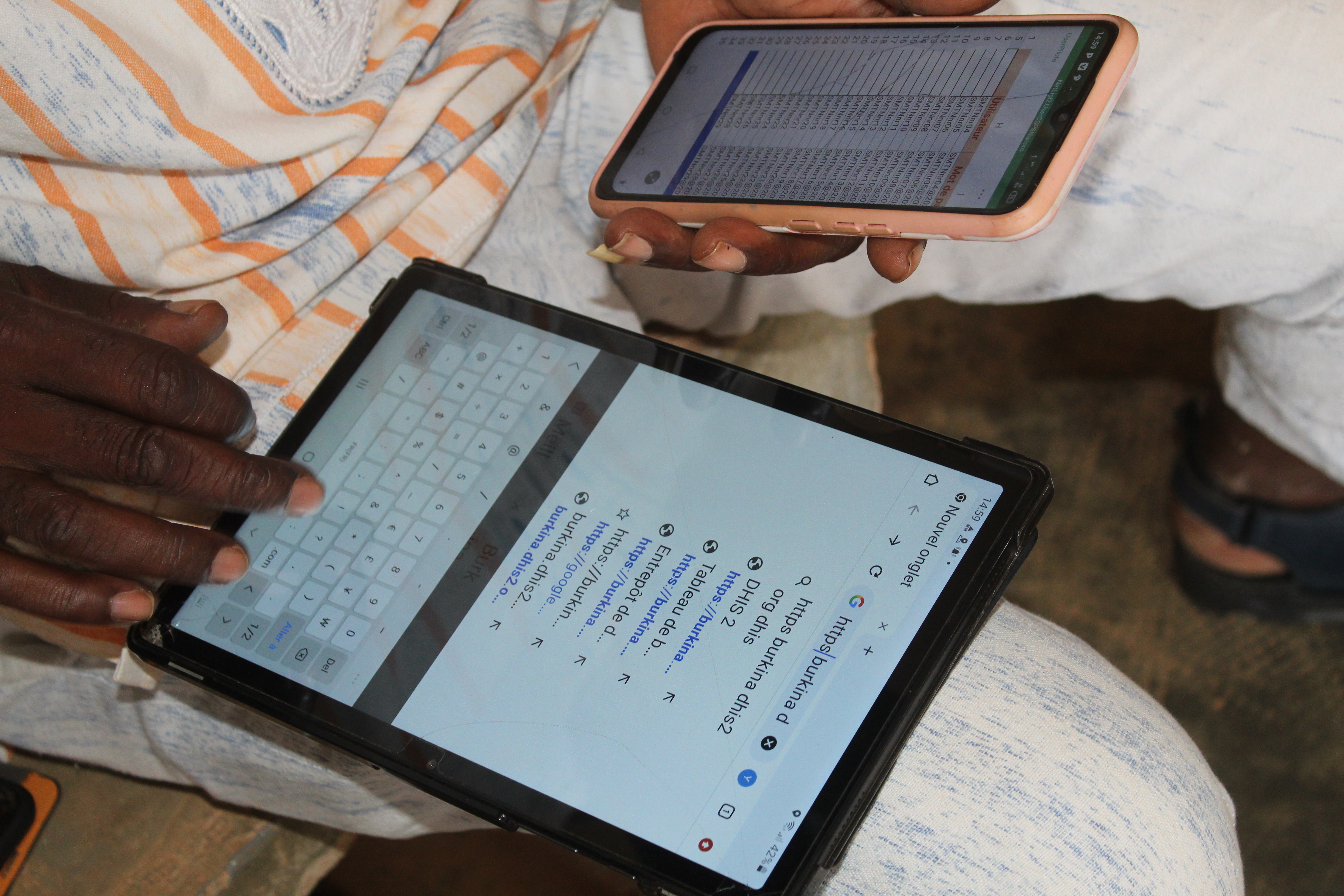 A healthcare worker has a tablet on his knee while using it to search the internet.