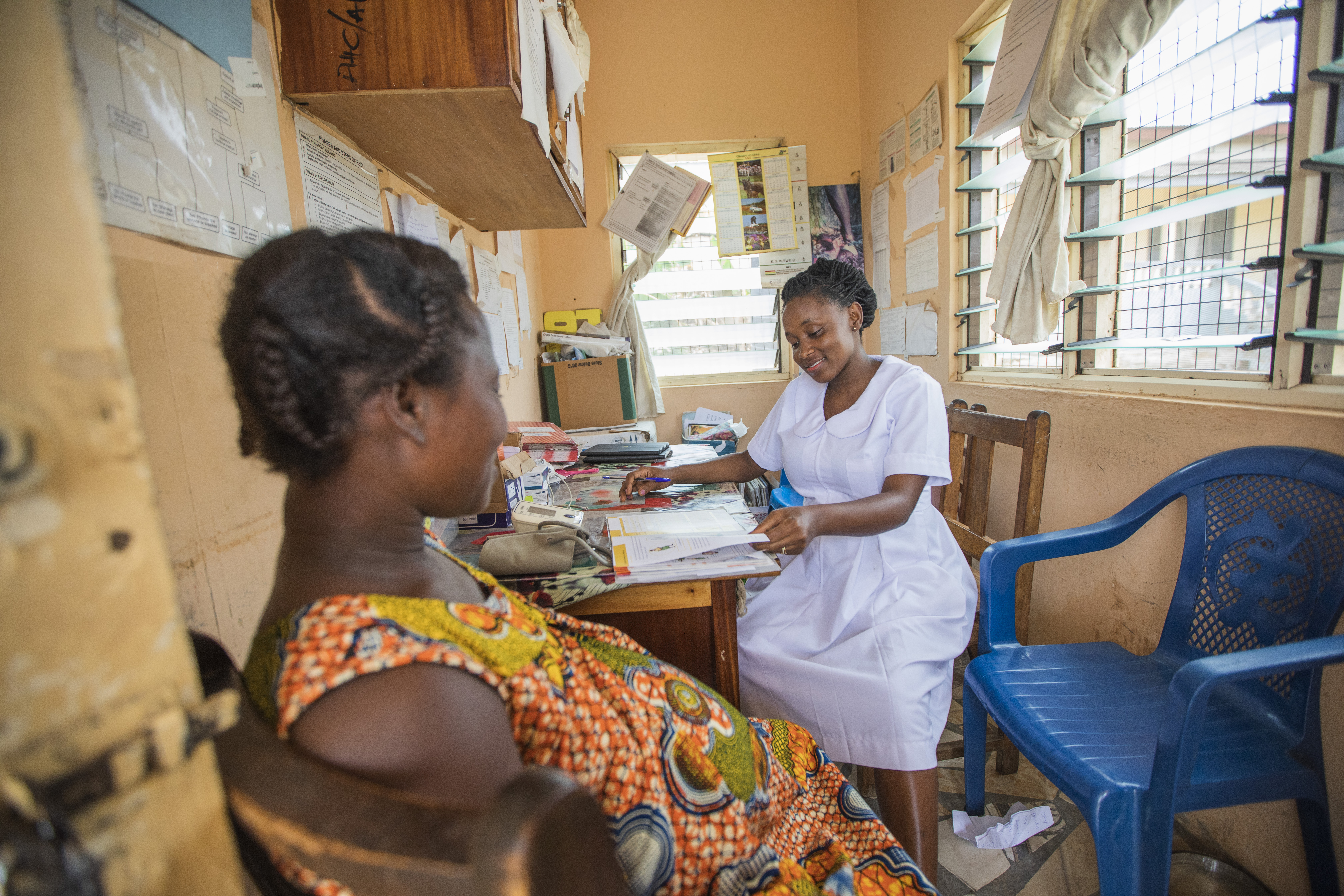 pregnant person in Ghana sits with health worker for in-clinic appointment