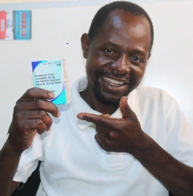 smiling man holds ARV medication