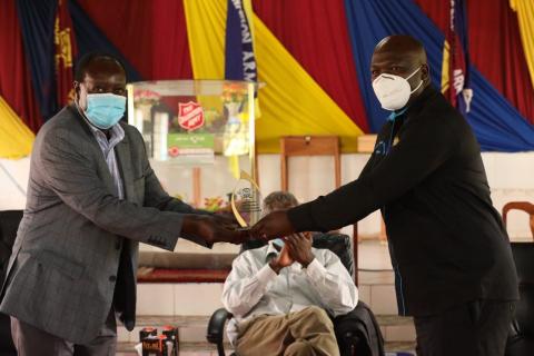 H.E. Governor Ottichillo presents overall best supply chain management performance award to a health worker.