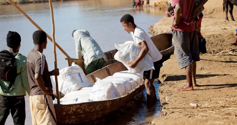 Men load insecticide-treated nets onto a boat.